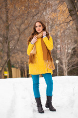 Fototapeta na wymiar Young beautiful woman in yellow coat walking winter park