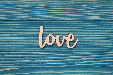 The word Love on a blue wooden background. Valentine's Day card concept. Flat lay composition.