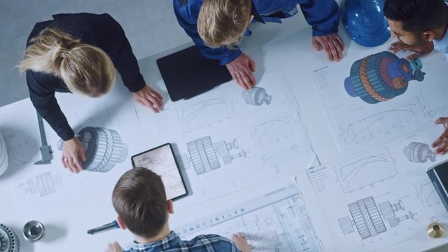 Team of Industrial Engineers Lean on Office Table, Analyze Machinery Blueprints, Architectural Problem Solving, Consult Project on Tablet Computer, Inspect Metal Component. Flat Lay Top Down View
