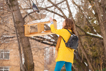 Young girl near bird feeder in winter park