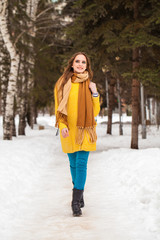 Fototapeta na wymiar Young beautiful woman in yellow coat walking winter park