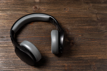 Headphones on dark wooden background. Black earphones, Top view