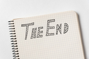 Notepad with the words The End on white background. Handwritten