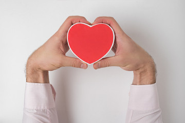 Obraz premium Small red heart shaped box in male hand on white background