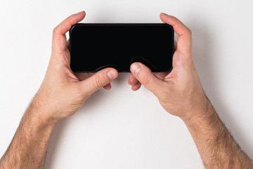 Man holding a smartphone. Empty black screen. White background, copy space