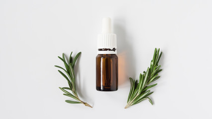 isolated glass bottle with aromatic oil and a sprig of rosemary on a white background