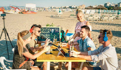 Happy friends having fun vlogging video live feed at beach party - Young influencer sharing content online with web cam on social media platforms - Modern technology concept on warm bright filter