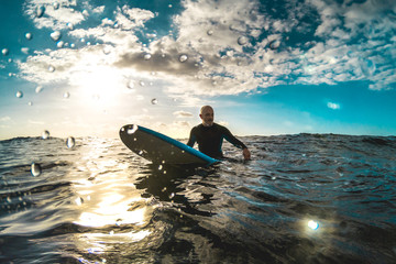 Surfer relaxing on surfboard at sunset in Tenerife waiting for the next good wave - Sport travel...