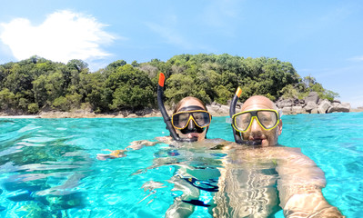 Young couple taking selfie in tropical scenario with waterproof camera - Boat trip snorkeling...