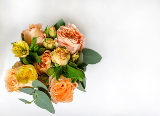flower arrangement of orange roses and green leaves of eucalyptus in a vintage pot on a white background. partial blur. concept of holiday, love, compliment