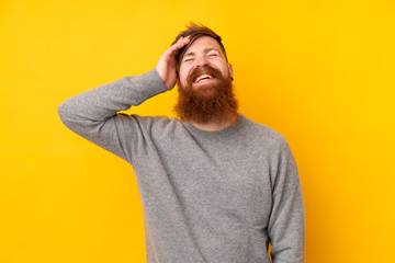 Redhead man with long beard over isolated yellow background smiling a lot