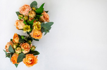 flower arrangement of orange roses and green leaves of eucalyptus in a vintage pot on a white...