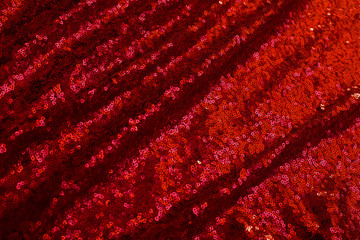 red background of shiny pleated fabric with blurred pleats