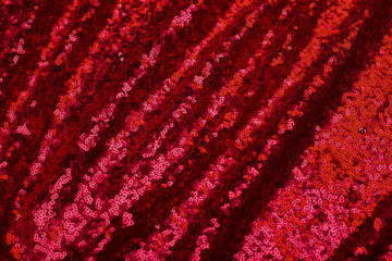 red background of shiny pleated fabric with blurred pleats