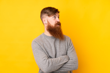 Redhead man with long beard over isolated yellow background portrait