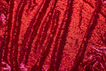 red background of shiny pleated fabric with blurred pleats