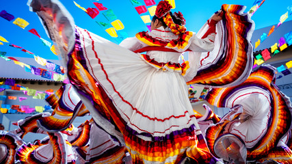 Photo of folklore dancers dancing in a beautiful traditional dress representing Mexican culture.