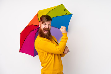 Redhead man with long beard holding an umbrella over isolated white background making strong gesture