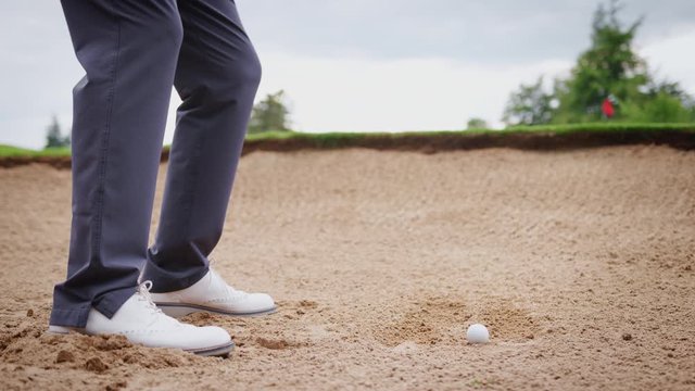 Close Up Of Male Golfer Hitting Golf Ball Out Of Bunker And Onto Green