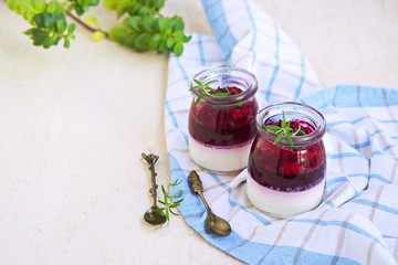 Dessert, creamy panna cotta with cherry sauce in in vintage glass jars on a light concrete background. Desserts without baking. Desserts for Valentine Day. Italian food