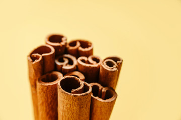 Cinnamon sticks on a yellow background. Very close, selective focus, there is a place for text