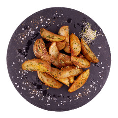 Baked potato wedges on black slate plate isolated on white background - homemade organic vegetable vegan vegetarian potato wedges snack food.