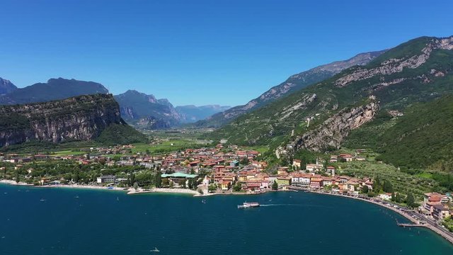 Flights over the windsurfers, coast of the city of Riva del Garda, Nago Torbole, Italy. Blue sky, rocks, strong wind. Aerial view. Flight by a drone. Ship along the windsurfers
