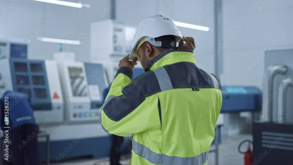 Poster industry 4 factory: modern worker wearing safety jacket puts on hard hat, walks through contemporary