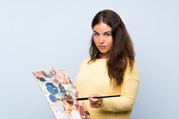 Young artist woman over isolated blue background