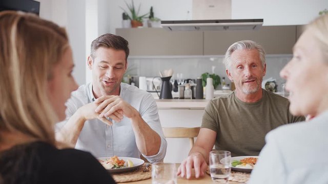 Family With Senior Parents And Adult Offspring Eating Meal Around Table At Home Together