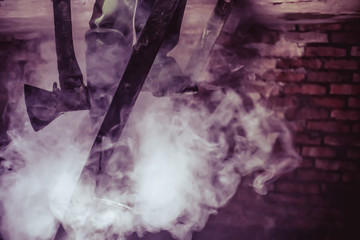 feet of a man in rubber boots with an axe in his hands on the stairs in the basement in the smoke....