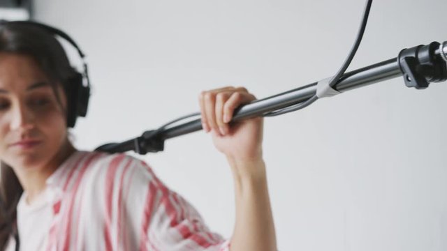 Female Sound Recordist Holding Microphone On Video Film Production In White Studio
