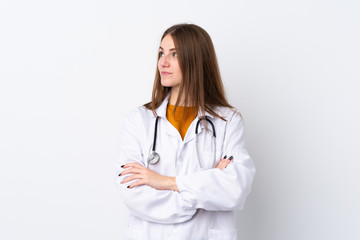 Fototapeta premium Young woman over isolated background wearing a doctor gown and with arms crossed looking side