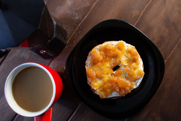 Bagel biscocho desayuno con mermelada de manzana y cafe en taza roja y cafetera italiana en mesa de madera