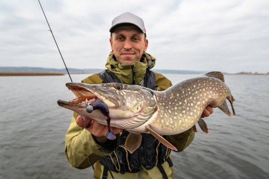 Happy fisherman with big pike fish. Boat fishing - Powered by Adobe
