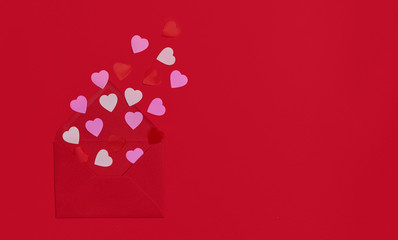 Red envelope with paper hearts. Romantic letter of declaration of love on a red paper background. Flat lay^ copy space fo text