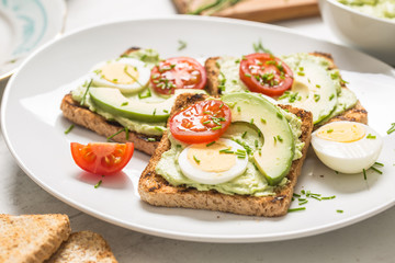 Fototapeta na wymiar Healthy breakfast from toasts with avocado spread guacamole egg tomato and chives.