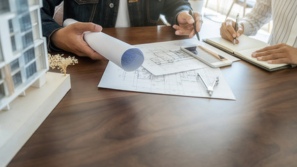 Engineer or architect teamwork working on construction project with building model and blueprint in office. Construction concept.