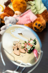Wedding dress, shoes and bridal bouquet are in mirror near of teddy bears