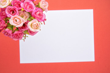 Greeting card bouquet of small roses with a white note, orange background. St. Valentine's Day