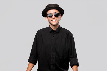 Portrait of a man in a black shirt, pork pie and sun glasses hat isolated over grey background.