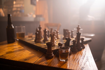 Old wooden chess board and drink on table in a pub