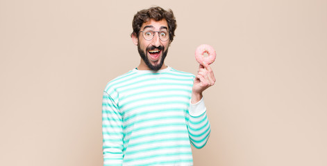 young cool man with a sugar pink donut against flat wall