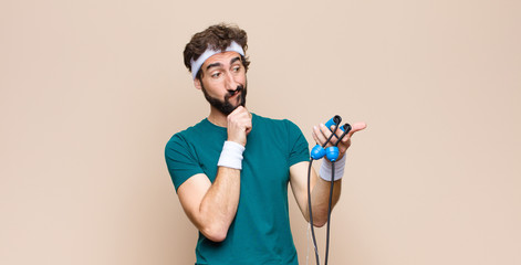 young cool sports man with a jump rope against flat wall