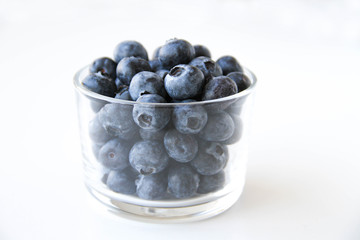 Fresh blueberries in a small glass on a white background. Healthy eating. Vegan food. Back view.