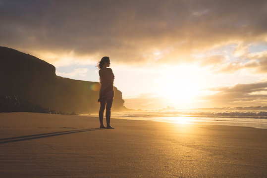Woman standing on the beach at sunset