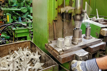 Skilled worker is separating pieces that come out of a die casting machine