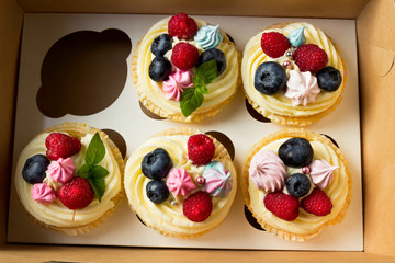 Delicious cupcakes with fresh berries in a box.