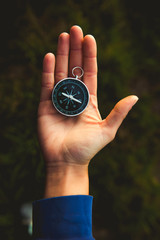 Girl Holding Travel Compass in Hand in Middle of Dark grass background and Nice Natural Light.