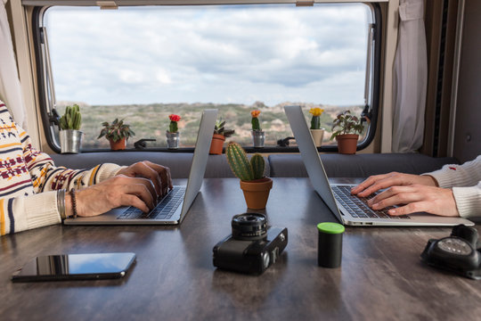 Crop view of couple working on laptops in camper, Es Mercadal, Menorca, Spain